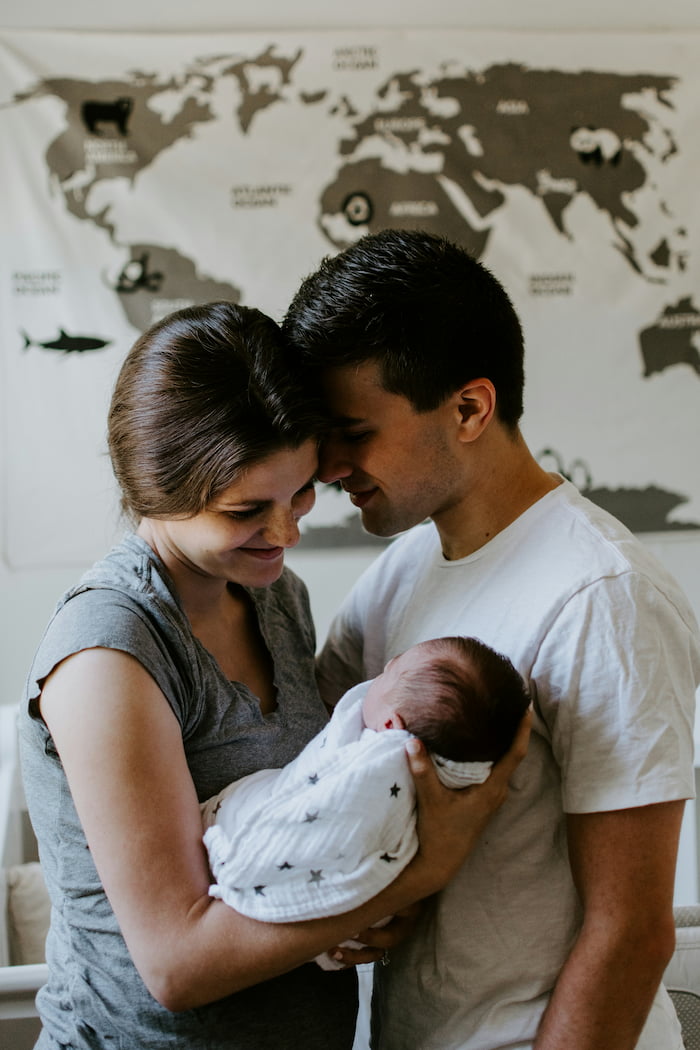 Newborn photography Houston - parents embracing their baby in tender family portrait