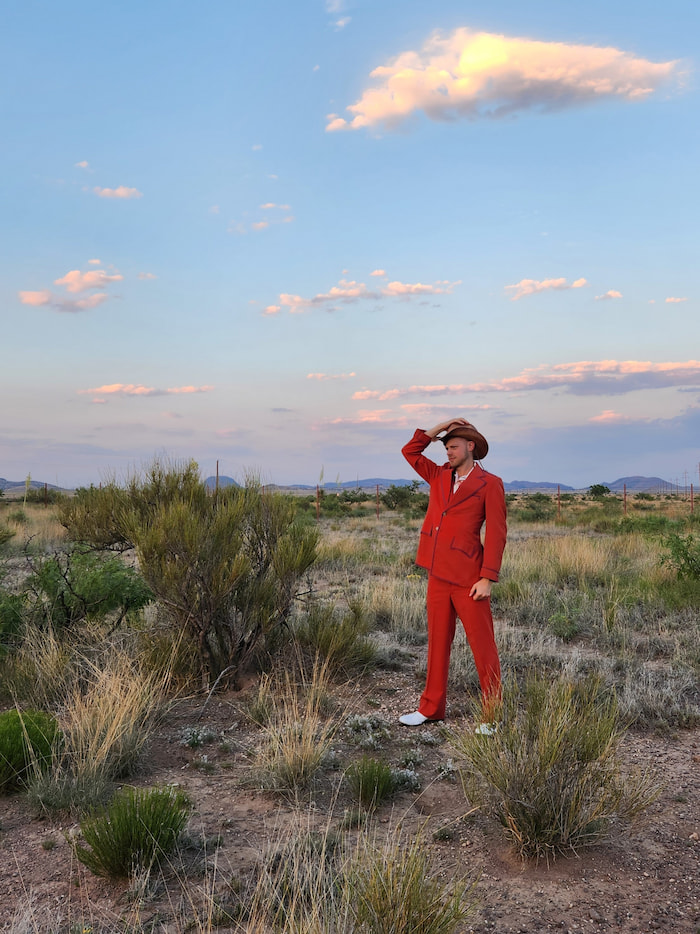 Fashion portrait photography Houston - man in vintage red suit and cowboy hat in desert landscape